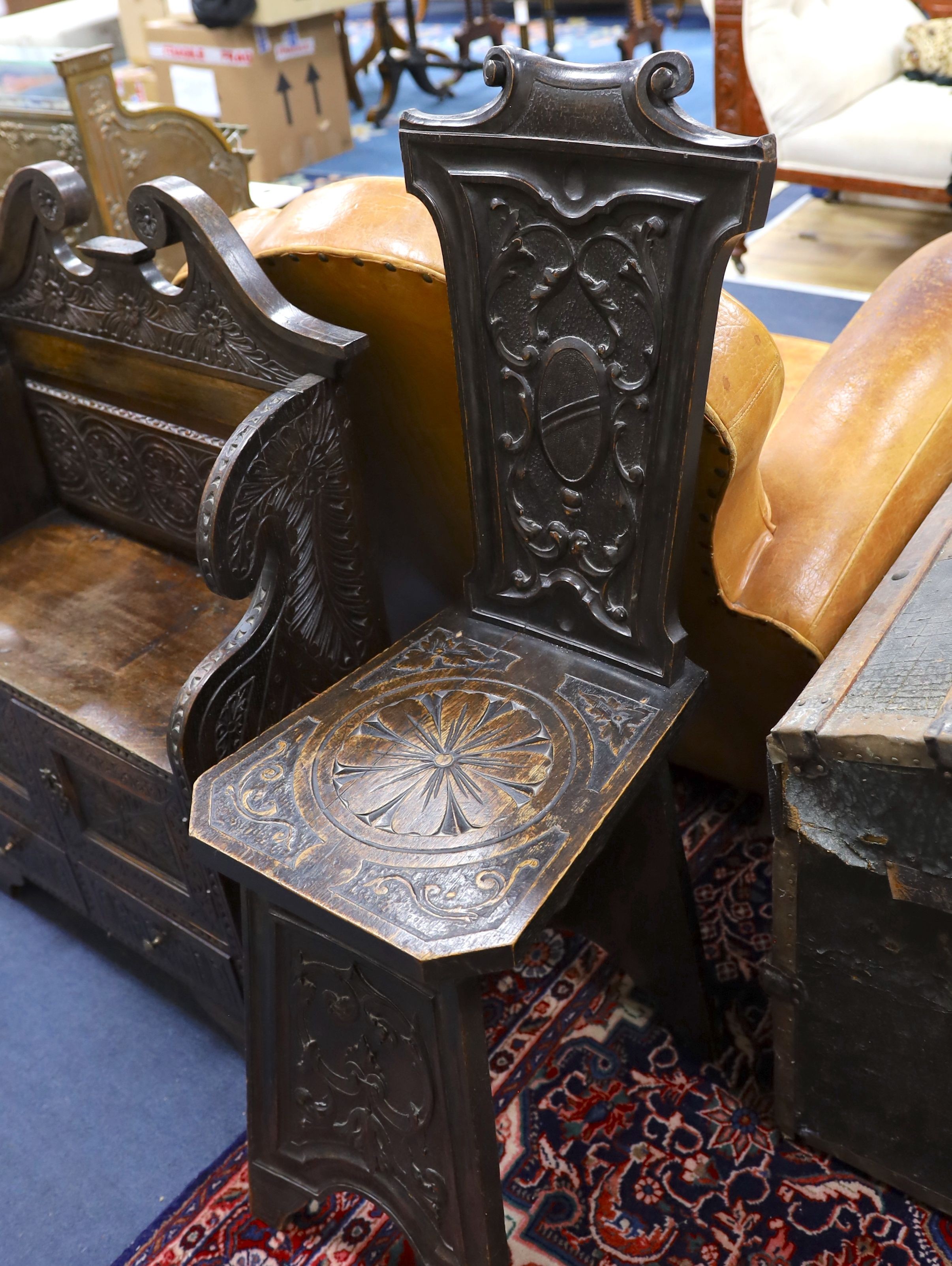 An early 20th century carved oak hall seat, width 64cm, depth 28cm, height 88cm together with two similar hall chairs